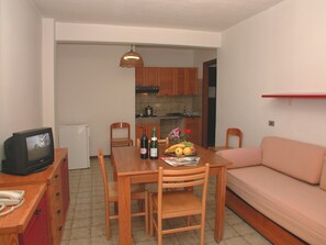 A compact living space with a dining table, chairs, a television, a kitchenette, and a sofa. - Residence Stella Maris (Pietra Ligure)