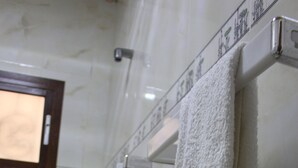 Une salle de bain avec une douche, une serviette suspendue à un porte-serviettes et une fenêtre avec un cadre en bois.