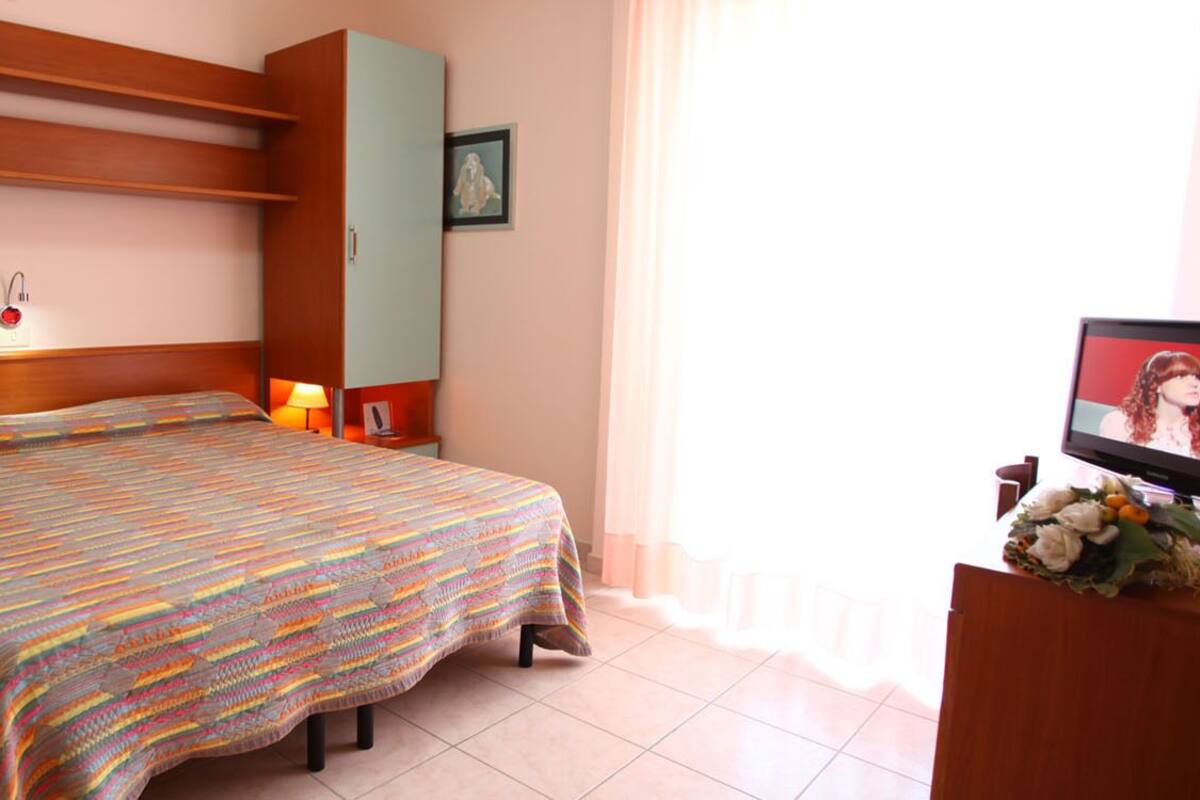 A bedroom with a bed, a nightstand, a TV, and a cabinet.