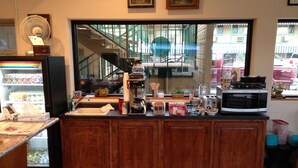 A kitchen with a large window, a refrigerator, a microwave, and various kitchen items on the counter. - Americas Best Value Inn (North Platte)