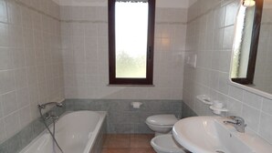 A bathroom with a bathtub, toilet, and sink. - AffittaSardegna - Casa Pompia 6 (Siniscola)