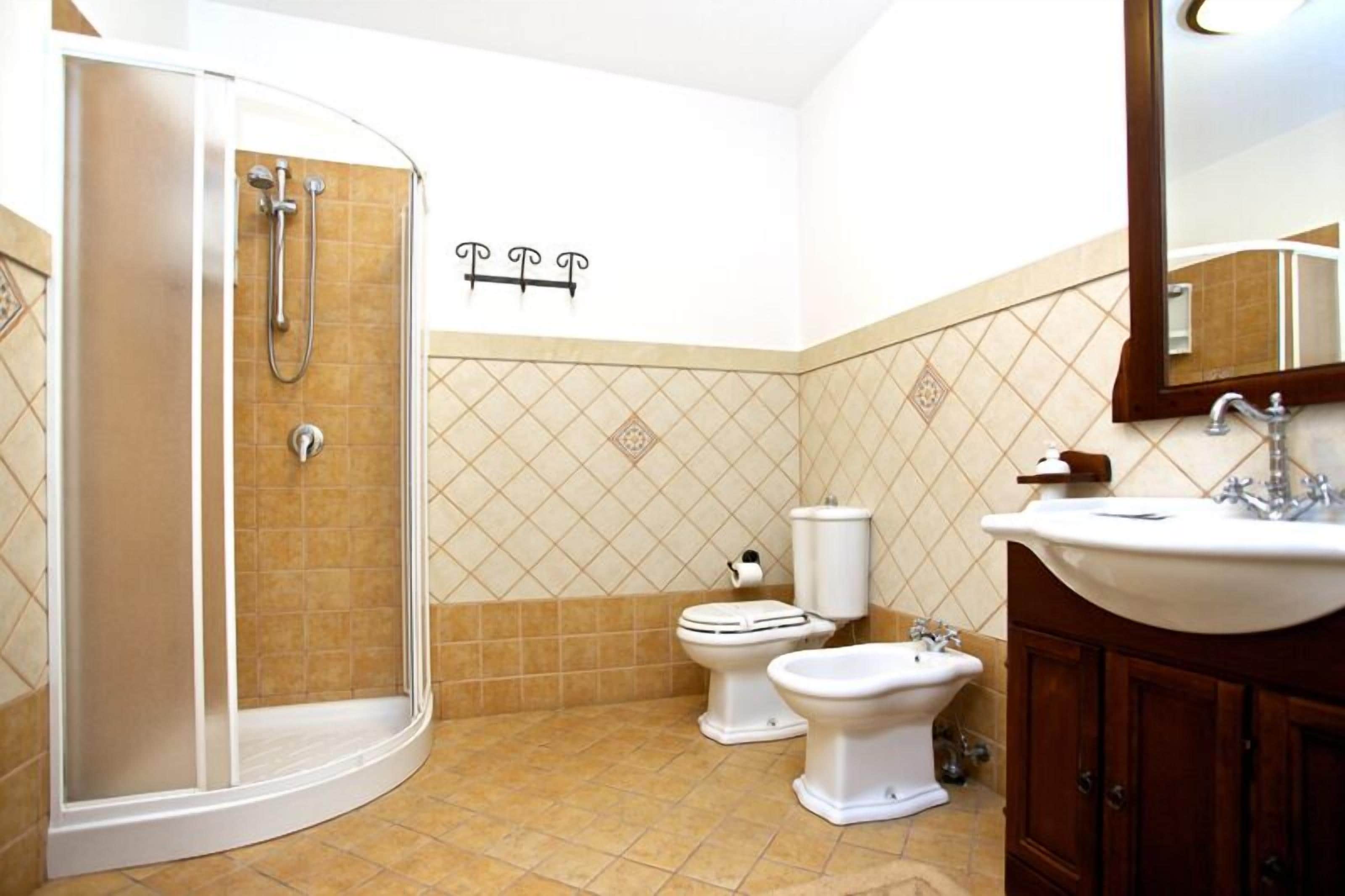 Une salle de bain équipée d’une douche, de toilettes, d’un bidet et d’un lavabo.