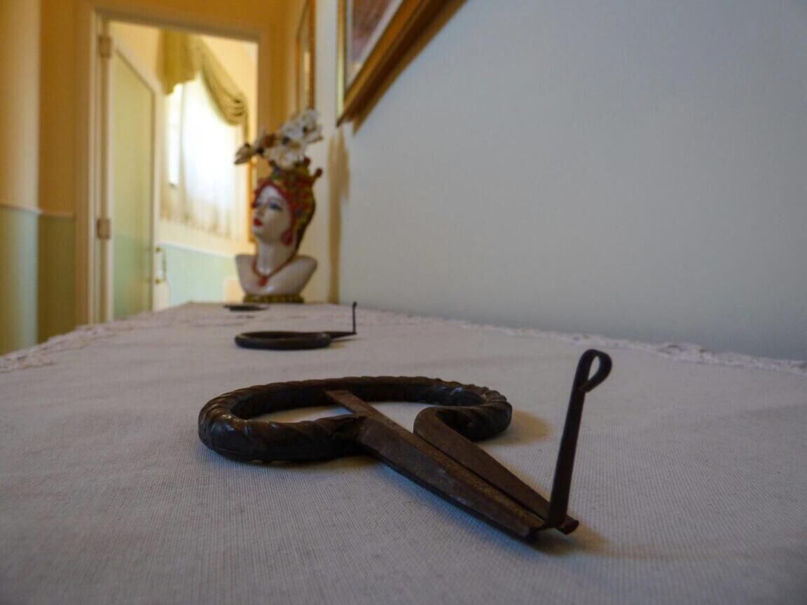 Een kamer met een bed, een borstbeeld en een schaar op het bed.