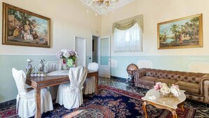 Una habitación con una mesa de comedor preparada para cuatro personas, un sofá y dos cuadros en las paredes.