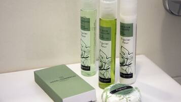 A set of green and white bottles labeled 'Figier fleur' and 'Fragonard' on a white surface, with a green box labeled 'HOTEL COMMERCIO'.