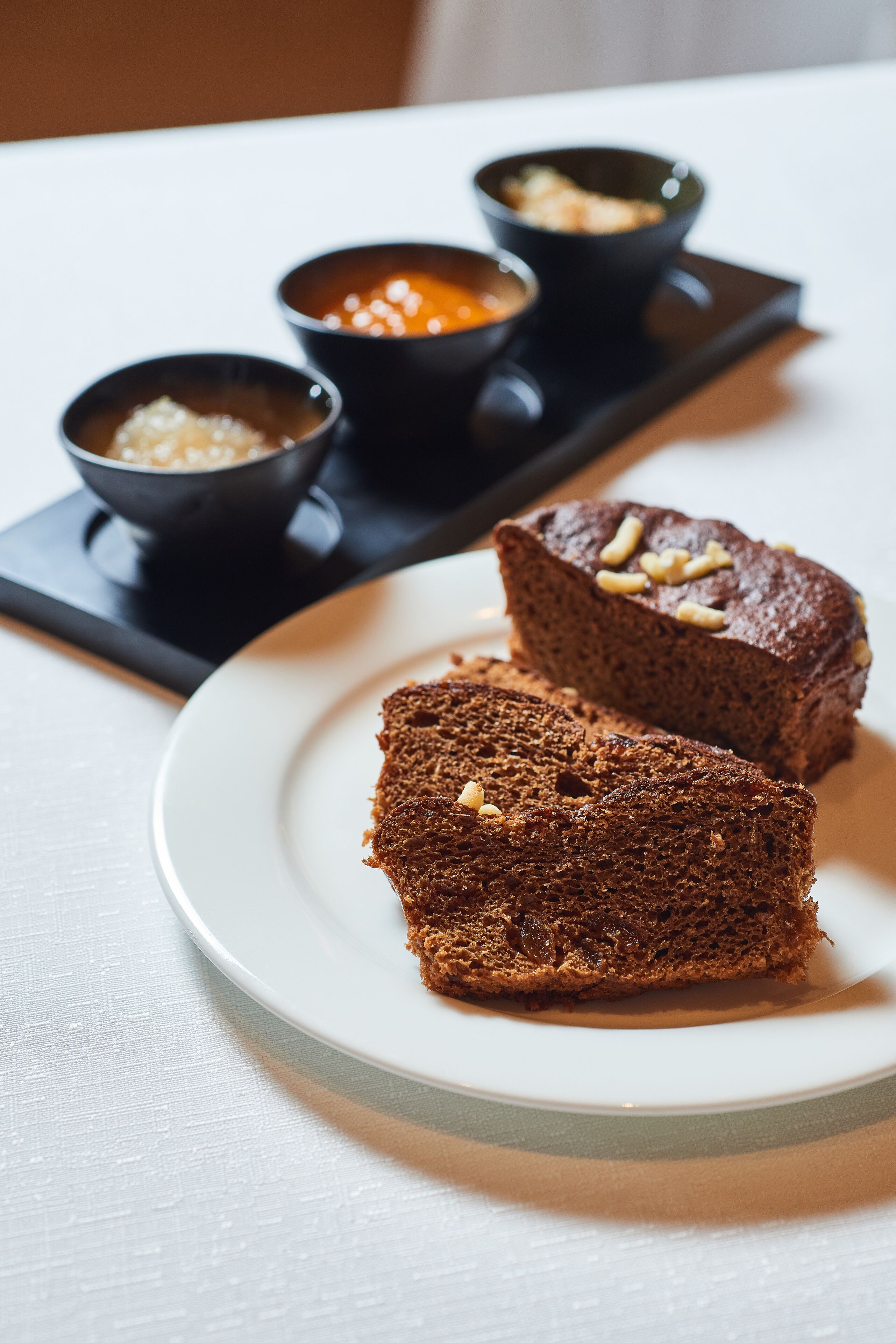 Une assiette avec deux parts de gâteau et trois petits bols contenant différentes sauces.