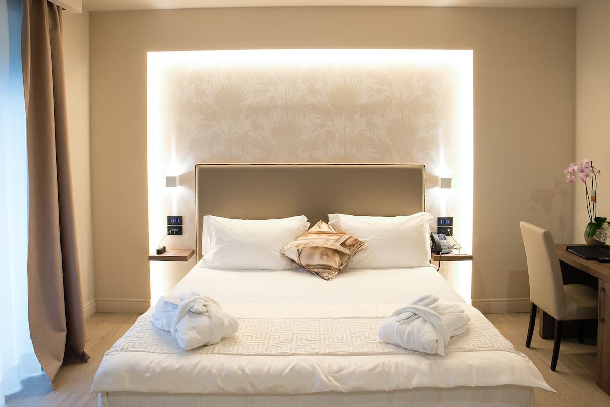 A hotel room with a large bed, a desk, and a chair.