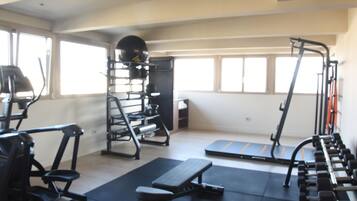 Une salle de sport équipée de divers appareils d’exercice, notamment des tapis de course, un banc de développé couché et des appareils de musculation.