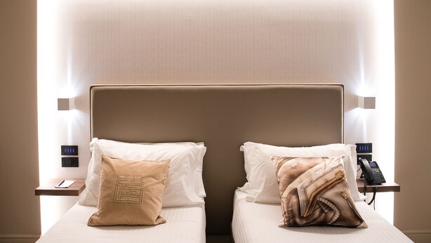 Une chambre d’hôtel avec deux lits, chacun étant équipé d’un oreiller et d’une table de chevet avec un téléphone.