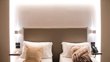 Habitación de hotel con dos camas, cada una con una almohada y una mesita de noche con un teléfono.