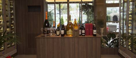 A bar area with a wooden counter, wine bottles, glasses, and a decorative light fixture.