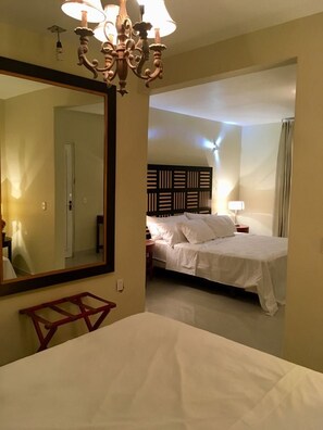 A hotel room with a large mirror, a bed with white linens, a wooden headboard, and a chandelier. - Hotel del Angel (Guadalajara)