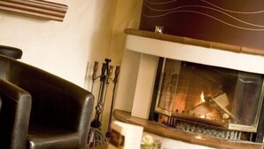 A cozy room with a fireplace, leather chairs, and a small table with a glass and a candle. - Hotel Donau (Donauwoerth)