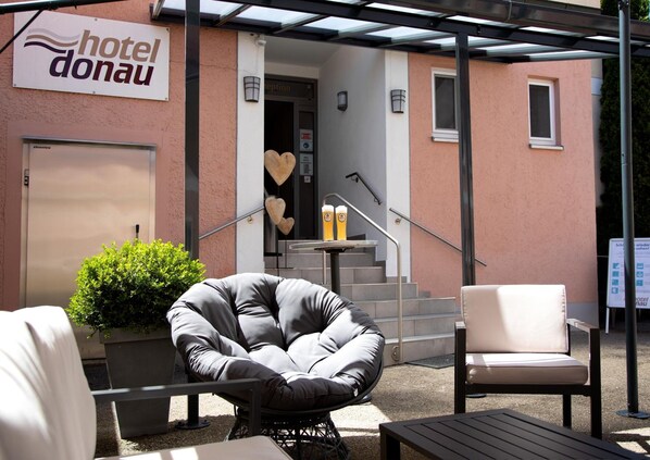 An outdoor seating area with a chair, a table, and a sign for 'hotel donau'. - Hotel Donau (Donauwoerth)