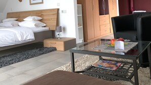 A modern bedroom with a bed, bedside table, and a glass coffee table with magazines. - Hotel Donau (Donauwoerth)