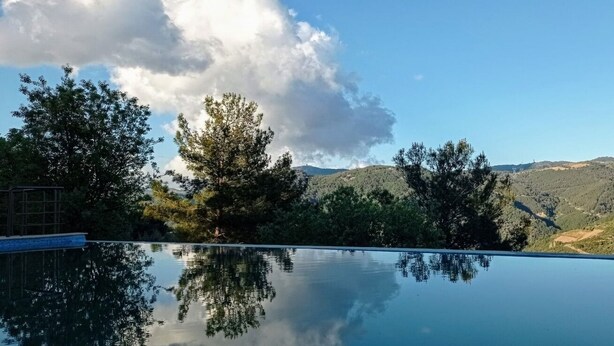 A clear view of a swimming pool with a mountain landscape in the background. - Godence Hotel Restoran (Seferihisar)