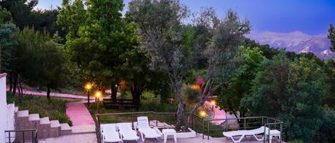 A poolside area with lounge chairs, a staircase, and a view of a mountainous landscape.