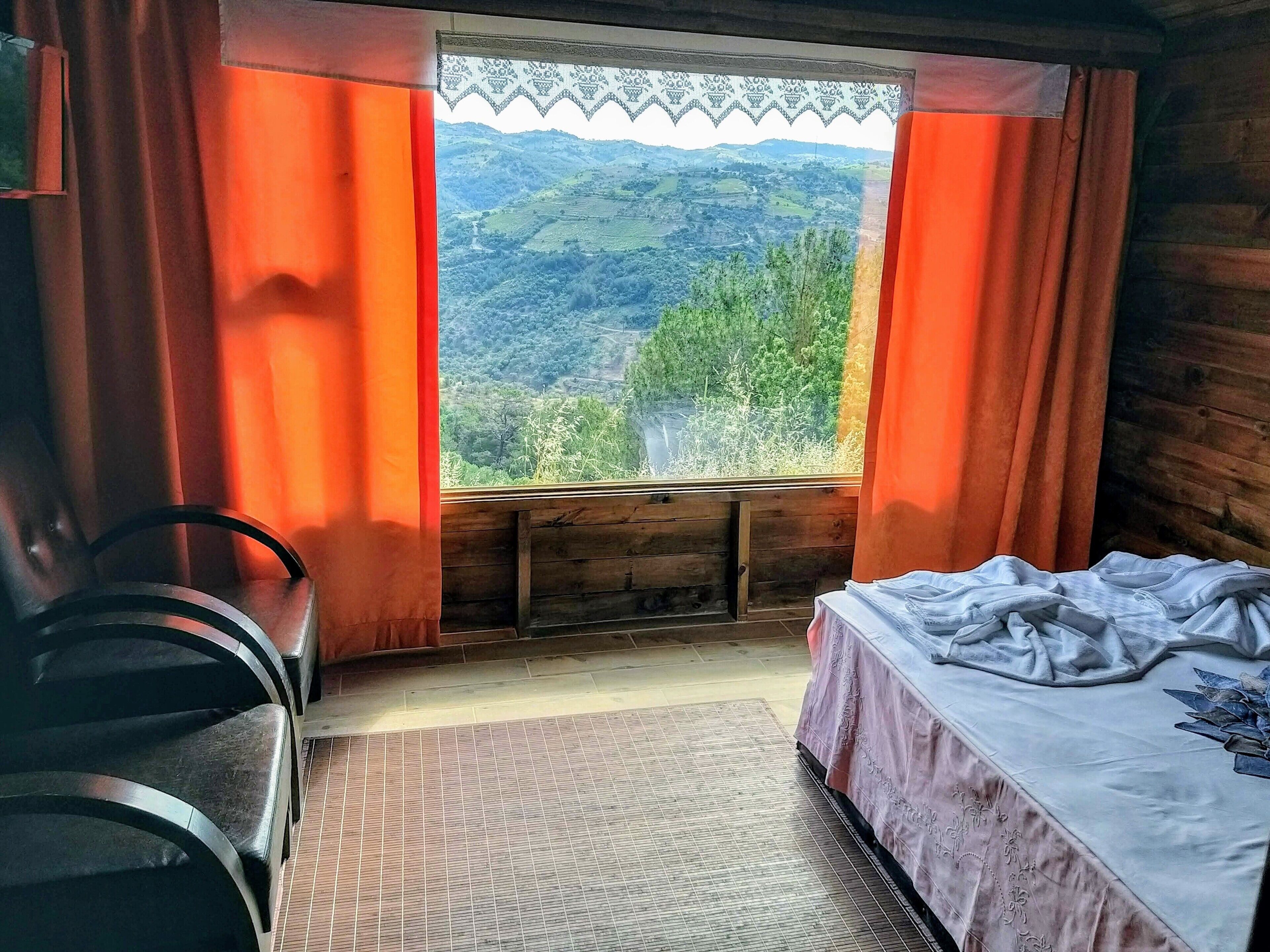A room with a bed, a chair, and a window with curtains.