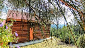 A wooden cabin with a red roof, surrounded by greenery and a clear view of the mountains. - Godence Hotel Restoran (Seferihisar)