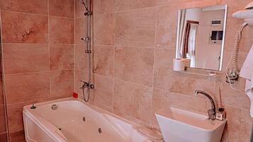 A bathroom with a bathtub, sink, and a mirror.
