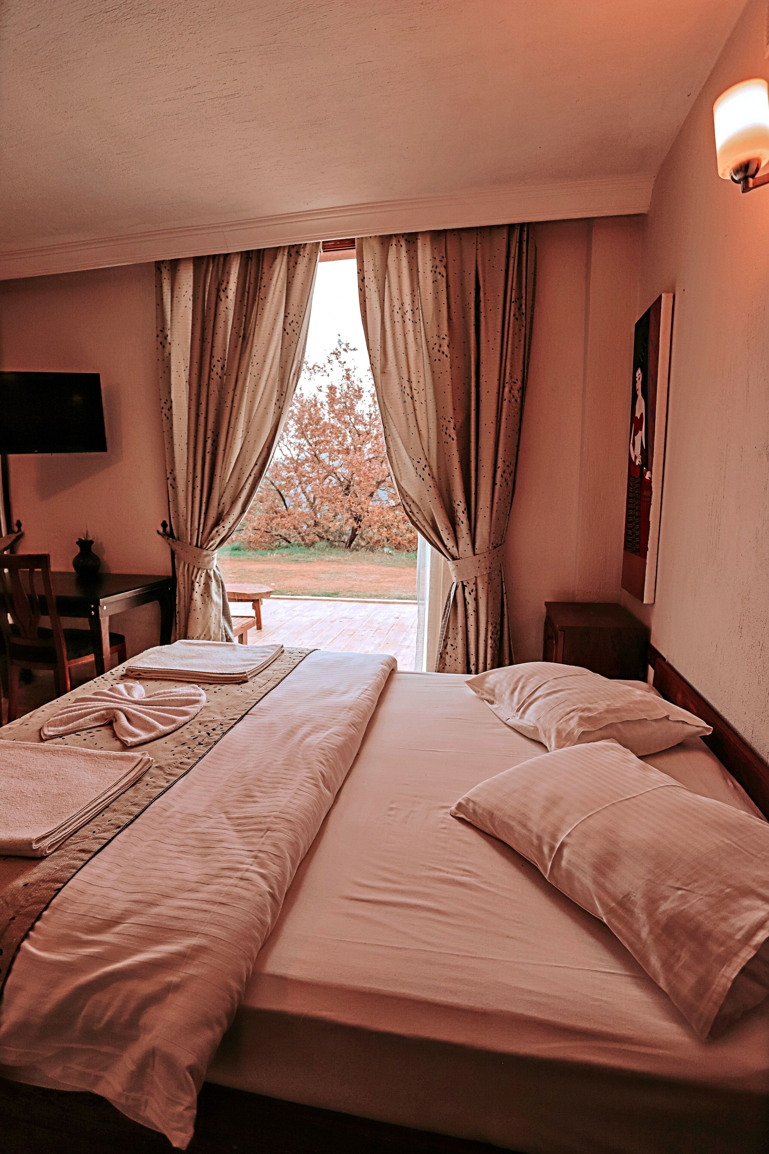 A hotel room with a bed, a desk, a chair, and a TV.
