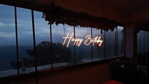 A room with a large window displaying a neon sign that reads "Happy Birthday." - Godence Hotel Restoran (Seferihisar)