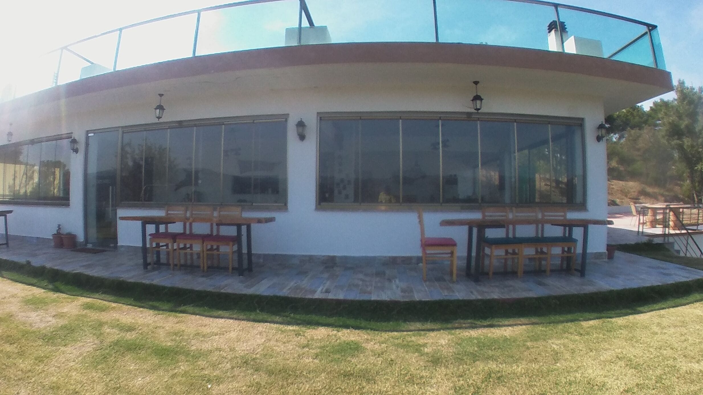 Een modern gebouw met grote ramen, buiten zitplaatsen en een overdekt terras.