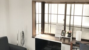 A modern living room with a large window, a flat-screen TV, a sofa, and a coffee table. - Tokyo Urban Flat Hotel 101 (Tokyo)