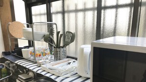 A kitchen with a microwave, a dish rack, and various utensils. - Tokyo Urban Flat Hotel 101 (Tokyo)