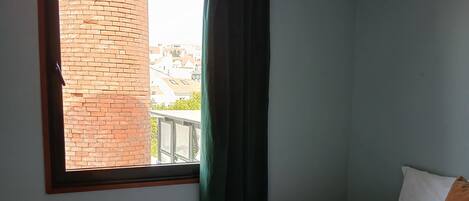 Un dormitorio con cama, una ventana con cortinas y una lámpara colgante.