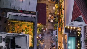 Luchtbeeld van een terras op een dak met buitenmeubilair, een zwembad en omliggend groen.