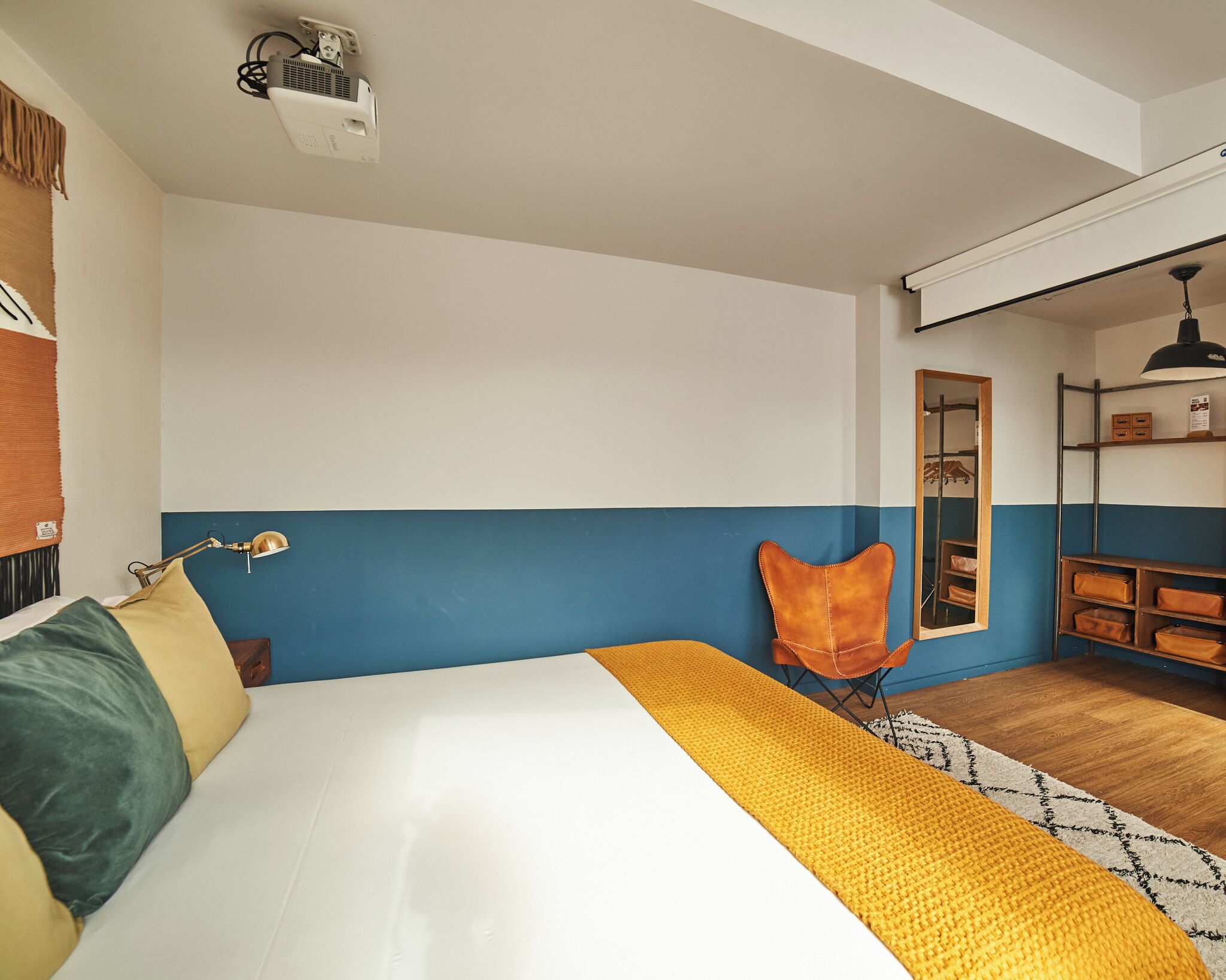 Quarto com cama, cadeira, escrivaninha e espelho.