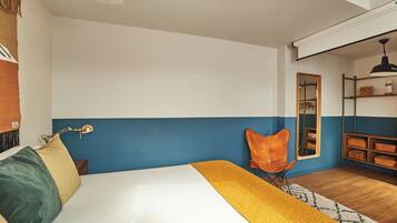 Quarto com cama, cadeira, escrivaninha e espelho.