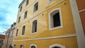 Een meerhoog gebouw met geel-witte buitenmuren, meerdere ramen, en een bordje dat cocktails en kiezels aangeeft.