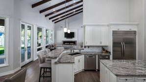 A modern kitchen with white cabinetry, a granite countertop, and a stainless steel refrigerator.