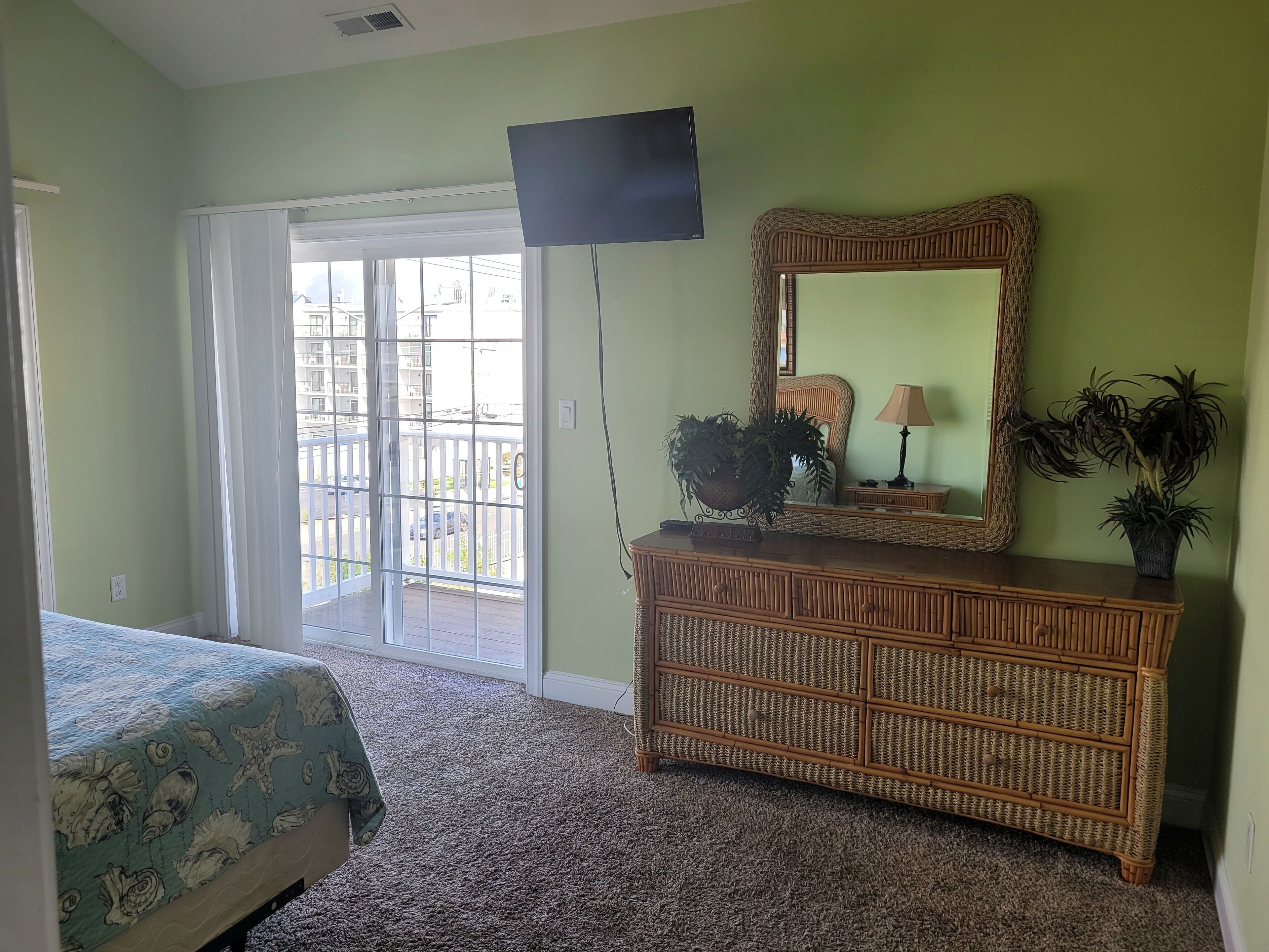 A bedroom with a bed, a dresser, a mirror, and a television.
