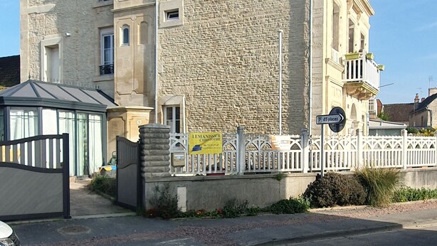 A multi-story building with a stone facade, a gated entrance, and a sign indicating 45 parking places. - Joyeux Reveil (Courseulles-sur-Mer)