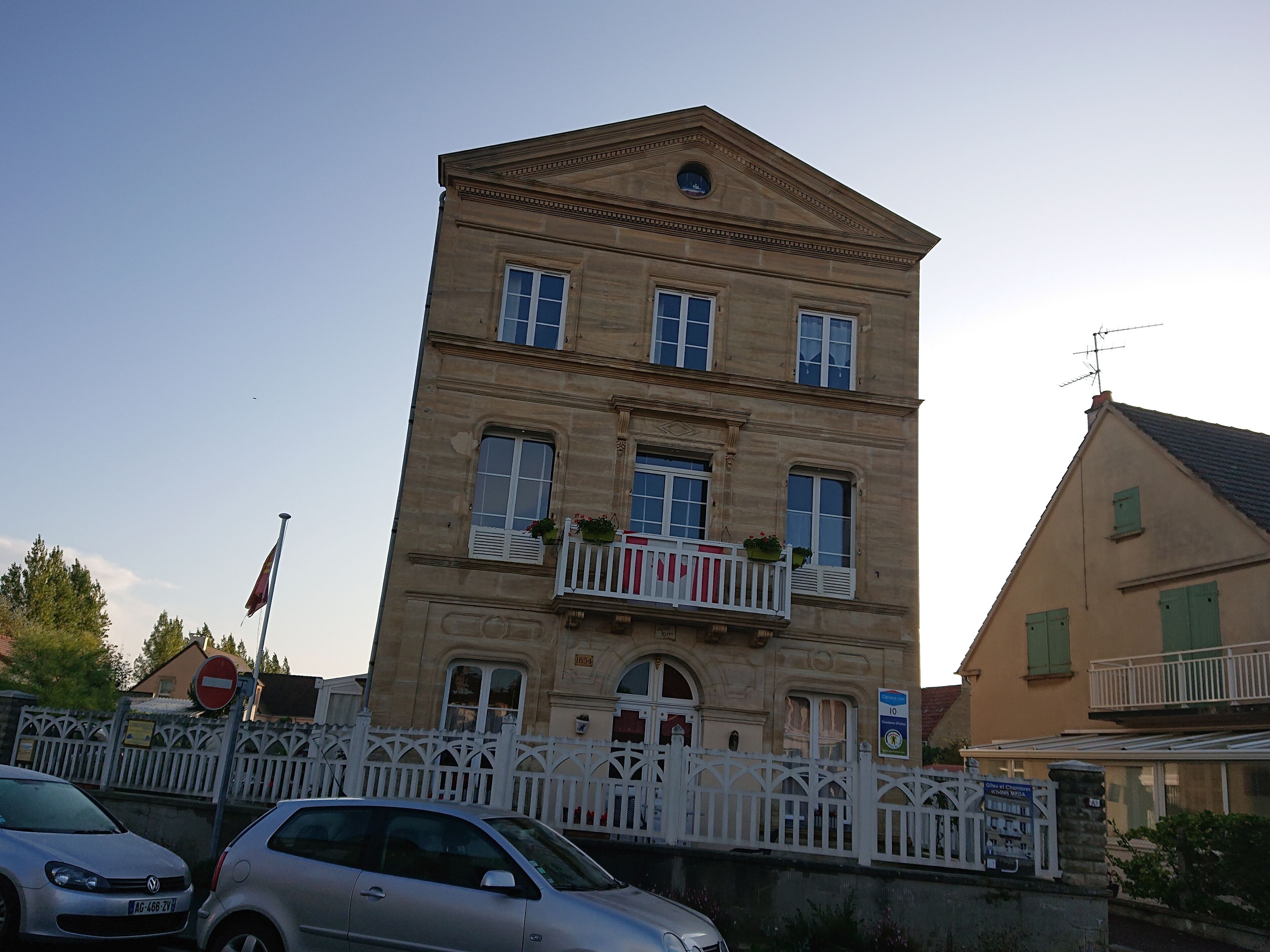 A multi-story building with a classical architectural style, featuring a balcony with potted plants.