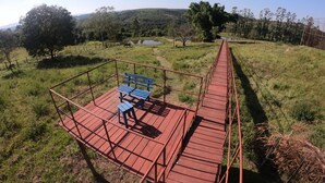 A wooden deck with benches overlooking a grassy field and a distant body of water.