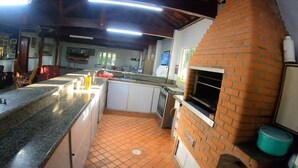 A kitchen with a brick oven, tiled floor, and a long counter.