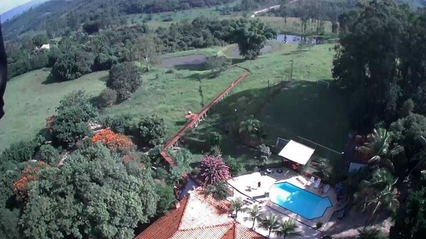 A residential area with a swimming pool, a red-roofed building, and surrounding greenery.