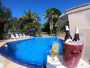 Un cadre agréable au bord de la piscine, avec un verre de bière, deux bouteilles et une piscine.