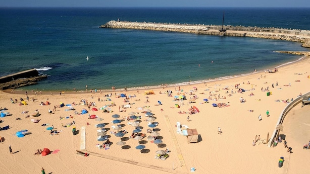 A beach with numerous umbrellas and people.