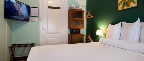 A hotel room with a bed, a television, a wooden cabinet, and a painting on the wall.