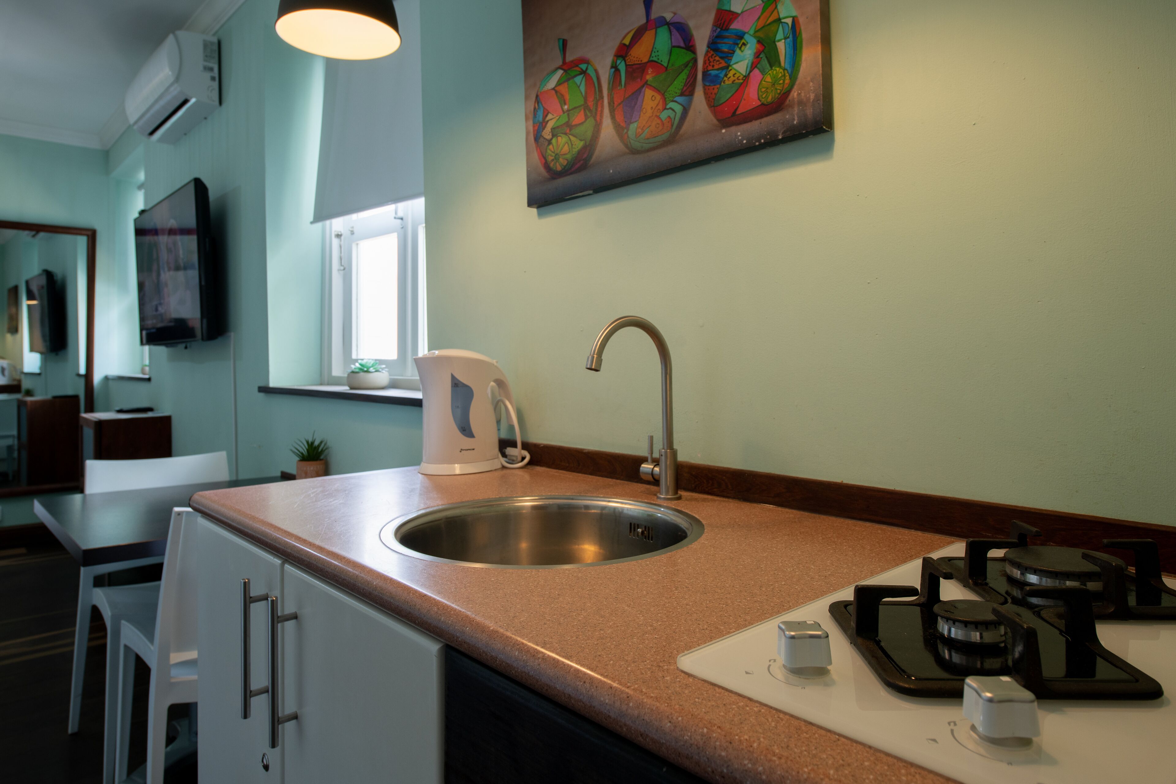 Een moderne keuken met een roestvrijstalen spoelbak, een koffiezetapparaat en een gasfornuis.