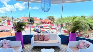 A covered outdoor seating area with white chairs and a sofa, patterned floor tiles, and a view of the cityscape. - Villa Amalie (Willemstad)