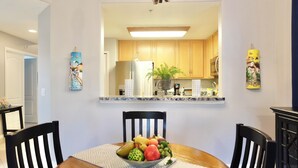 A dining area with a round table, chairs, and a fruit bowl. - Cozy apart in a quiet neighborhood, with beautiful views. (NAPLES)