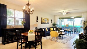 A spacious living room with a dining area, a chandelier, and a balcony with large windows. - Cozy apart in a quiet neighborhood, with beautiful views. (NAPLES)