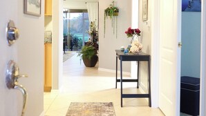 A hallway with a patterned rug, a potted plant, and a small table with flowers. - Cozy apart in a quiet neighborhood, with beautiful views. (NAPLES)