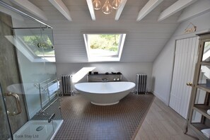 A modern bathroom with a freestanding bathtub, a glass shower enclosure, and a skylight. - West Lodge (Fort William)